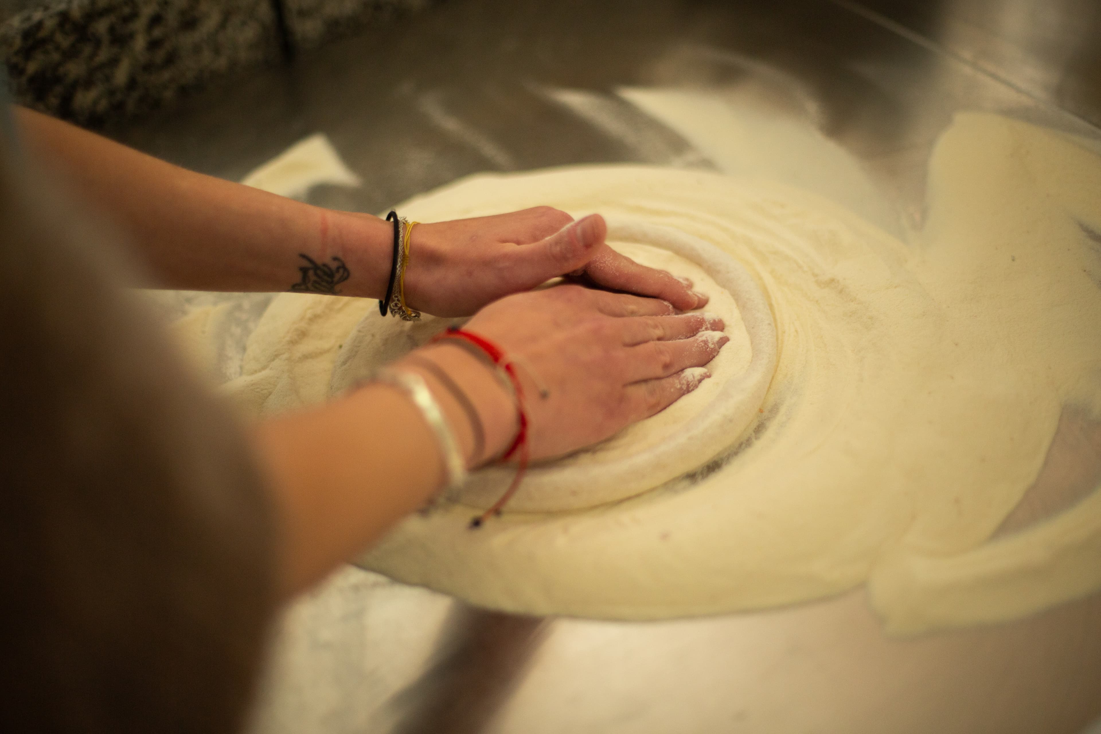 Mains travaillant une pâte à pizza sur un plan de travail — technique de boulage professionnelle