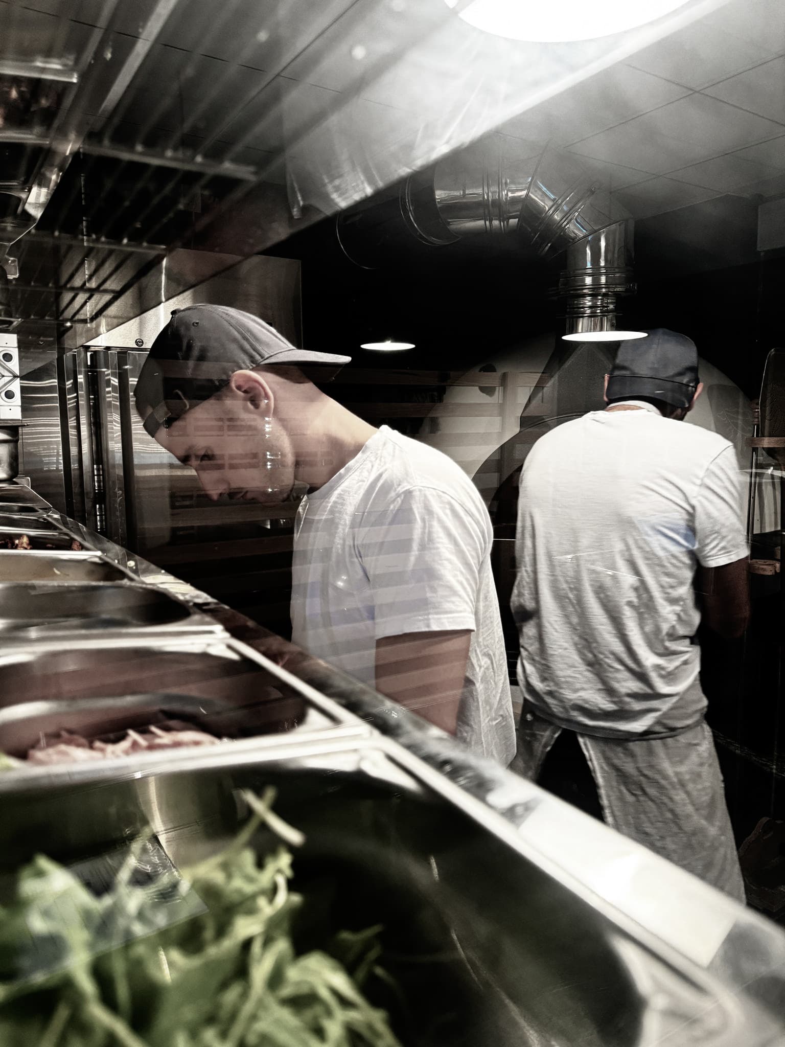 Pizzaiolo en action pendant un service — préparation de pizzas en cuisine professionnelle